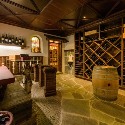 Cozy wine cellar with wooden shelves, barrel, seating area and rustic stone flooring.