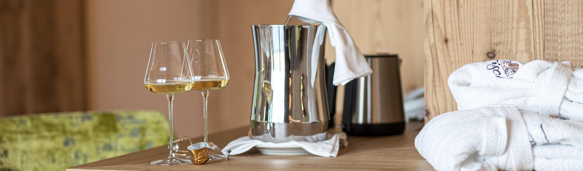 Two glasses of white wine, a chilled bottle in ice bucket, and bathrobes