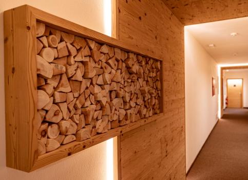 Hallway with warm lighting, wood elements, and decorative stacked firewood in a wall frame.