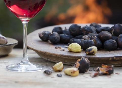 Un calice di vino rosso e un piatto con caldarroste