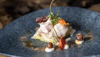 Fein angerichtetes Kalbfleisch mit Kapernapfel, Wurzelchips, Kresse und Oliventupfern.