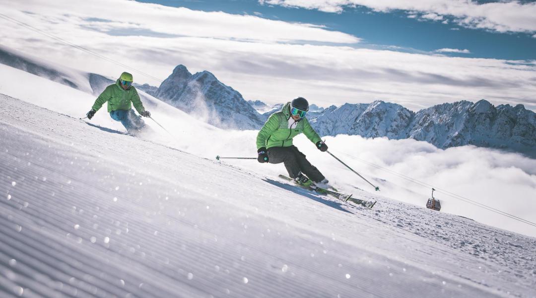 Two men are discending a ski slope