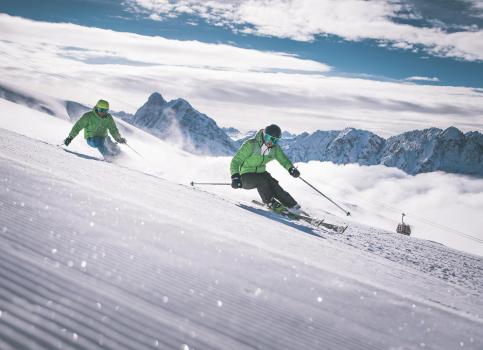 Two men are discending a ski slope