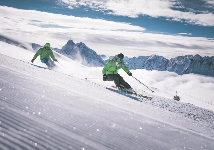 Two men are discending a ski slope