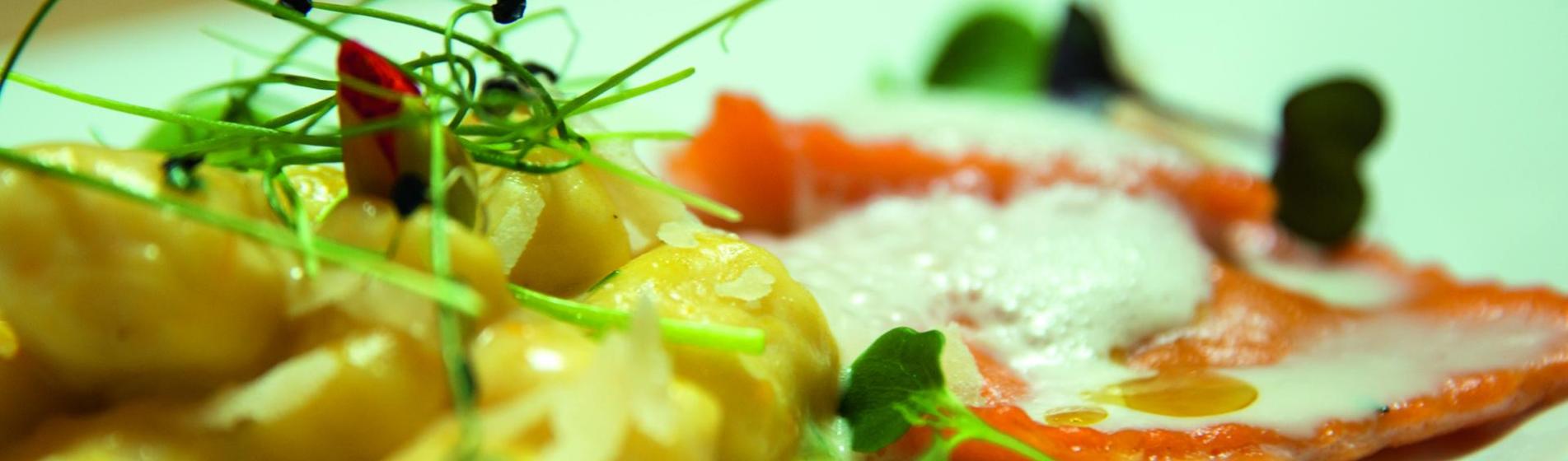 Gnocchi con salsa gialla e ravioli rossi con schiuma, guarniti con germogli