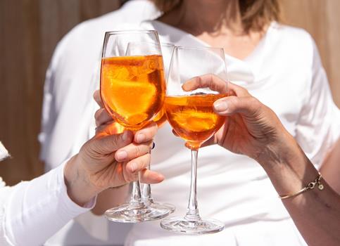 Three people are toasting with Aperol Spritz