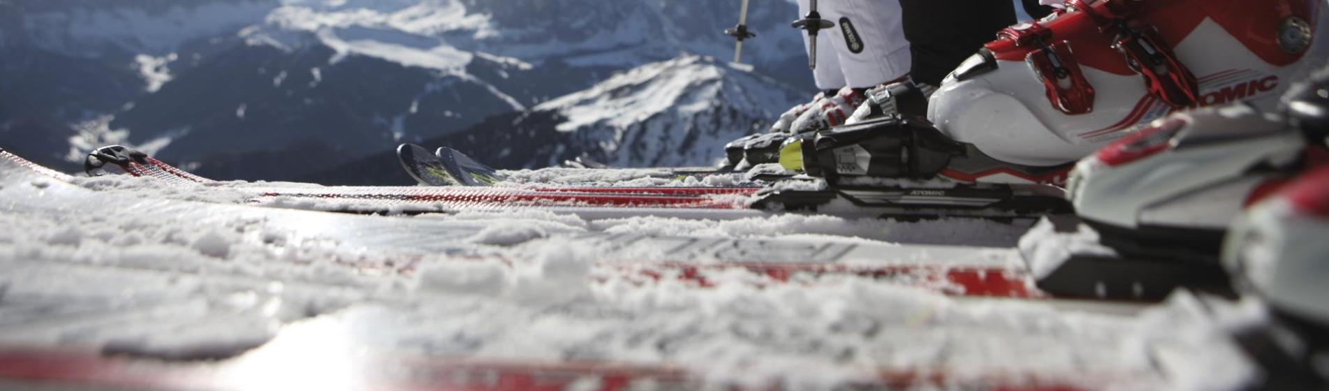 Skiers ready on a mountain top with a view of the snowy Dolomites and bright winter sun.