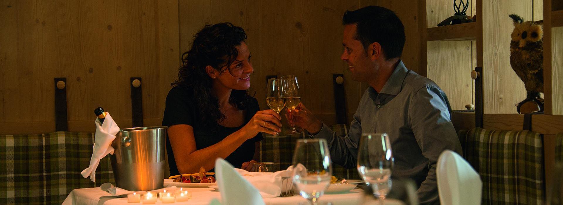 Two guests are clinking their wine glasses during a meal