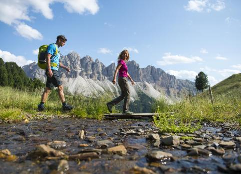 Two hikers are crossing a stream