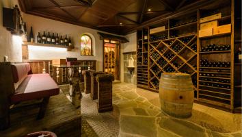 Cozy wine cellar with wooden shelves, barrel, seating area and rustic stone flooring.