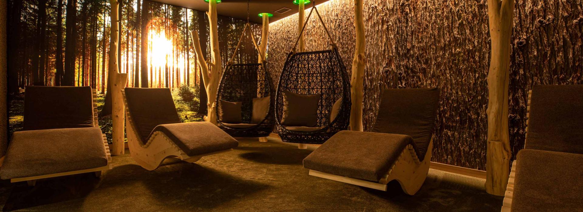Cozy relaxation room with wooden loungers and hanging chairs, bathed in warm, natural light.