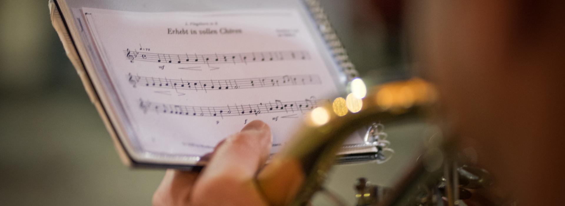 Primo piano di un musicista con spartito e strumento a fiato durante un'esecuzione.