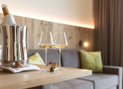 Two glasses of white wine with a chilled bottle on a wooden table in one of our suites