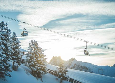 Paesaggio invernale con seggiovia, alberi innevati e montagne
